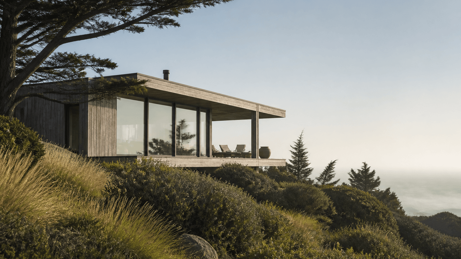 A low timber and concrete house sitting in a Northern California hillside landscape at late afternoon
